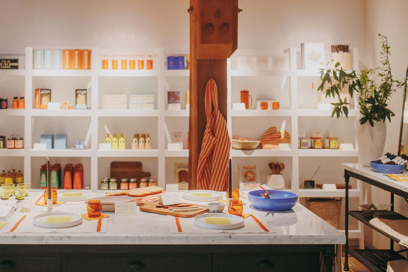 Supper Club pop up shop. In the foreground, a table with various food and cooking related products, with additional products on shelves in the background.