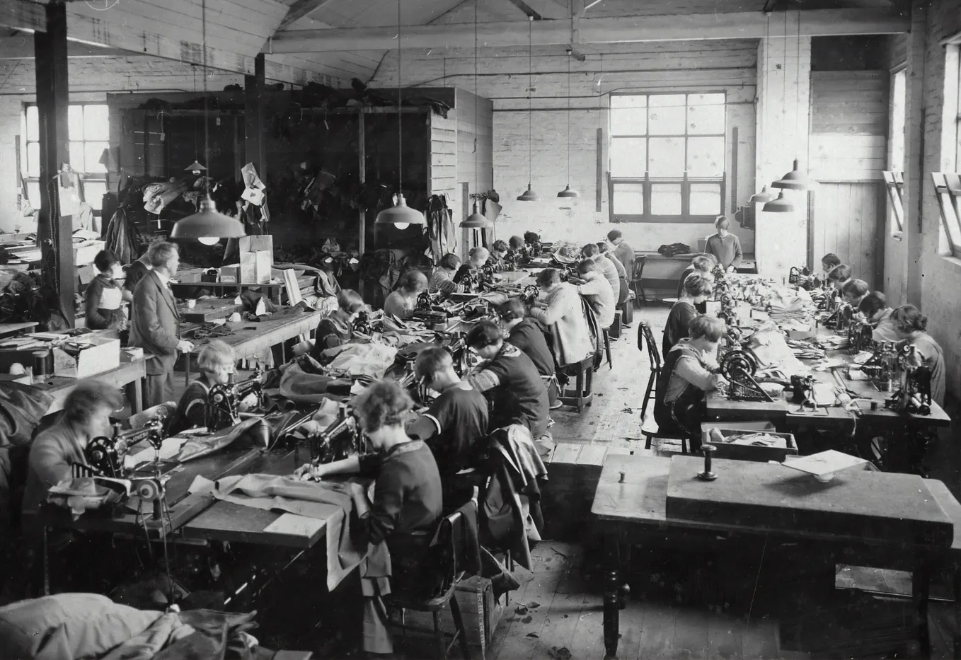 A vintage black-and-white photo of a room full of garment workers hard at work.