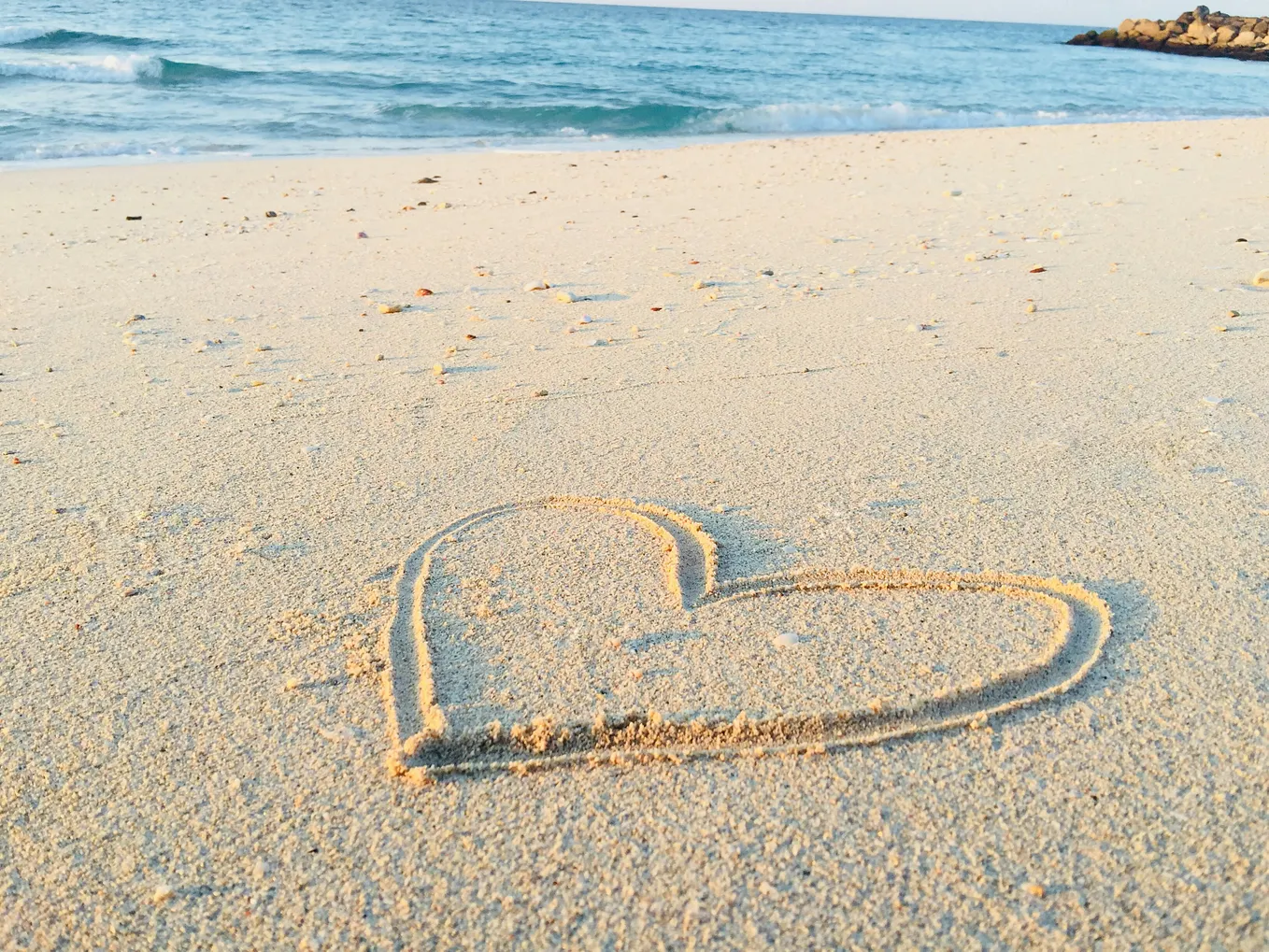 A heart drawn in the sand at the beach at low tide