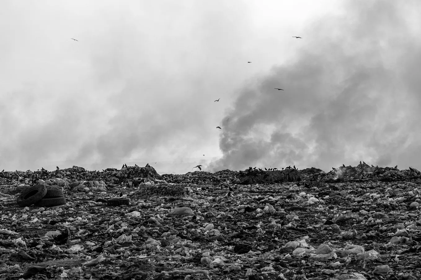 Photo: Large trash pile, some of which is on fire.