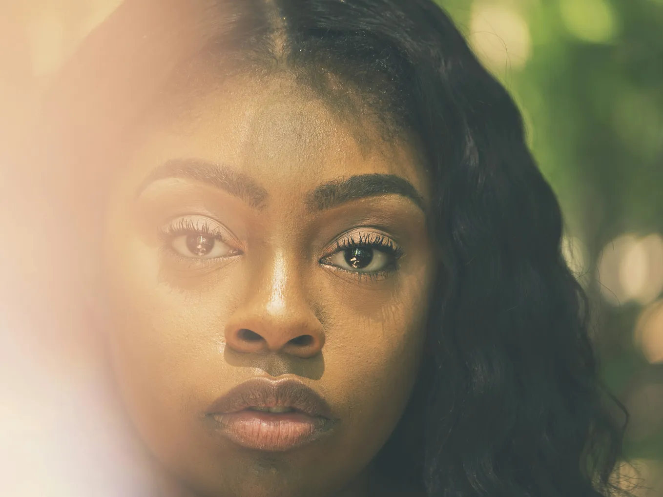 The face of a Black woman with wet eyes as she peers at the camera