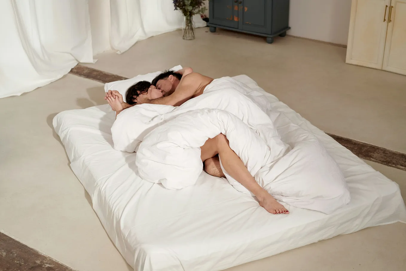 A white sheet set covering a heterosexual couple who’s sleeping