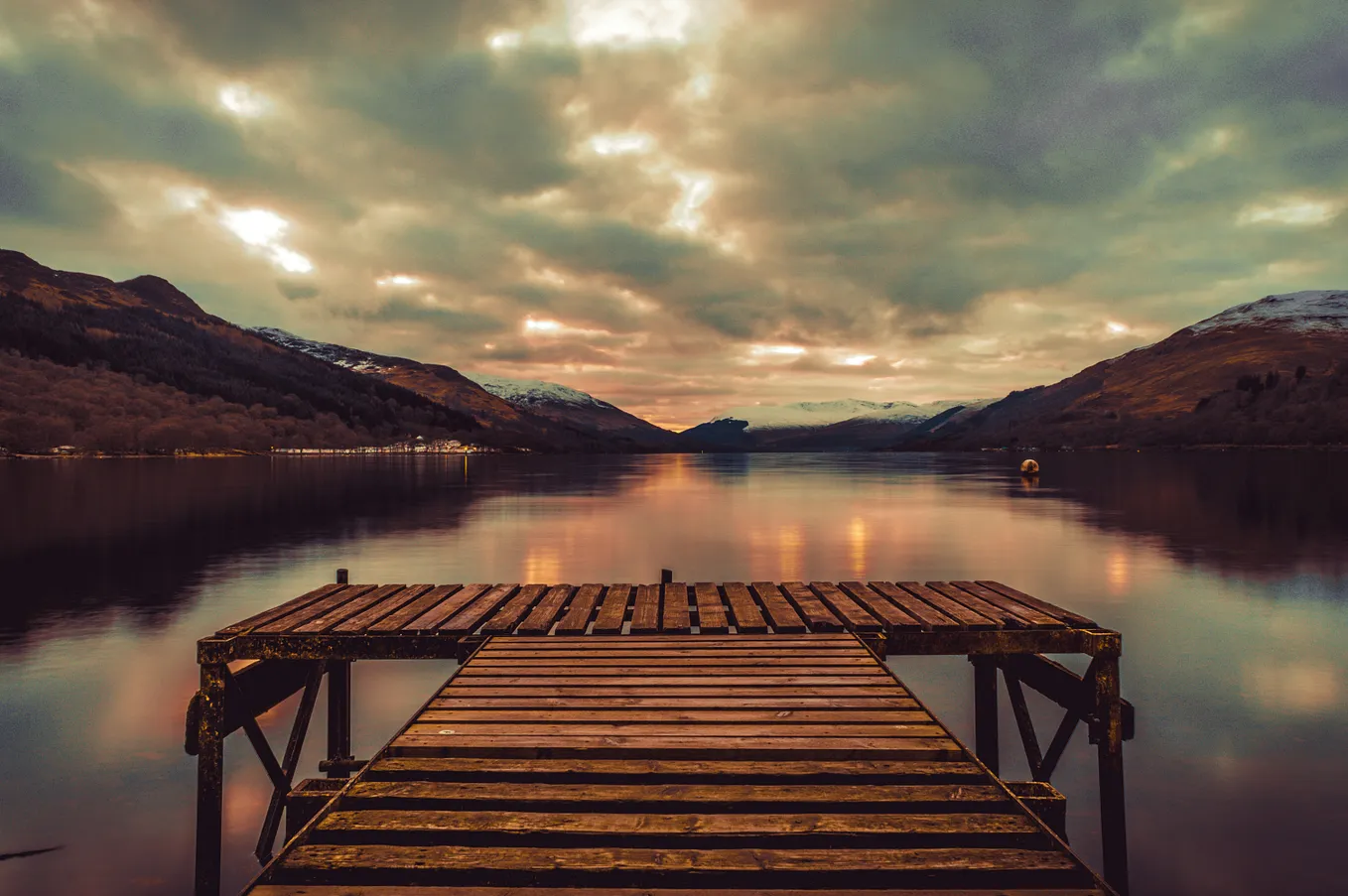 An empty dock over peaceful blue waters and a sky of billowy clouds