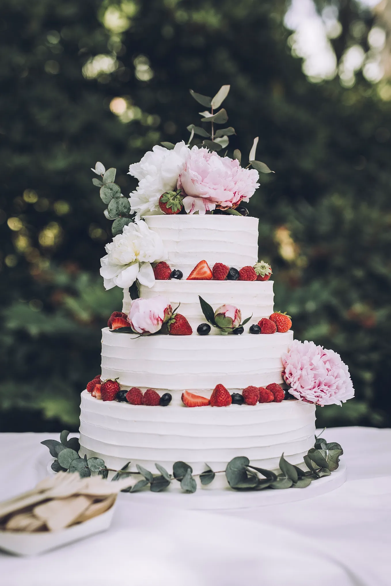 Layer cake with white frosting, fresh fruit, and fresh flowers