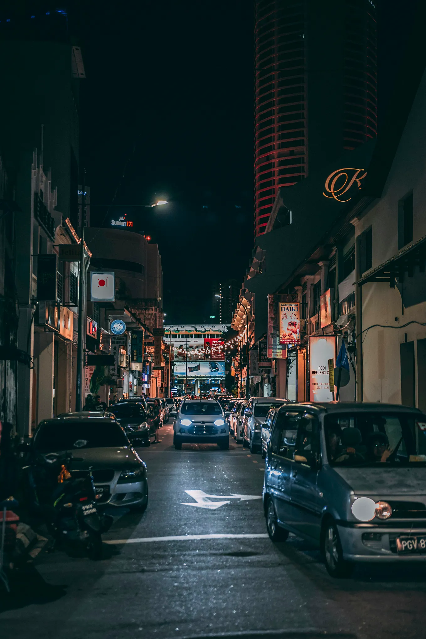 Many cars are parked on the street. Night.