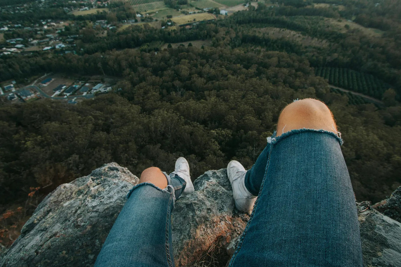 A man sitting at the edge of a cliff, contemplating his life plans.