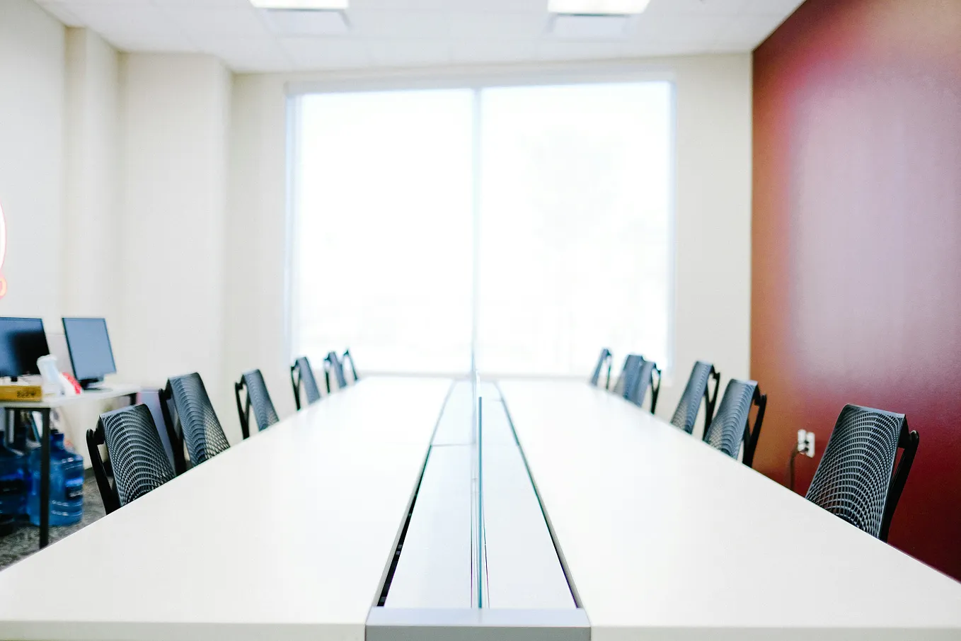 One person sitting at a conference table set for ten, representing a solo founder doing the work of a full team.