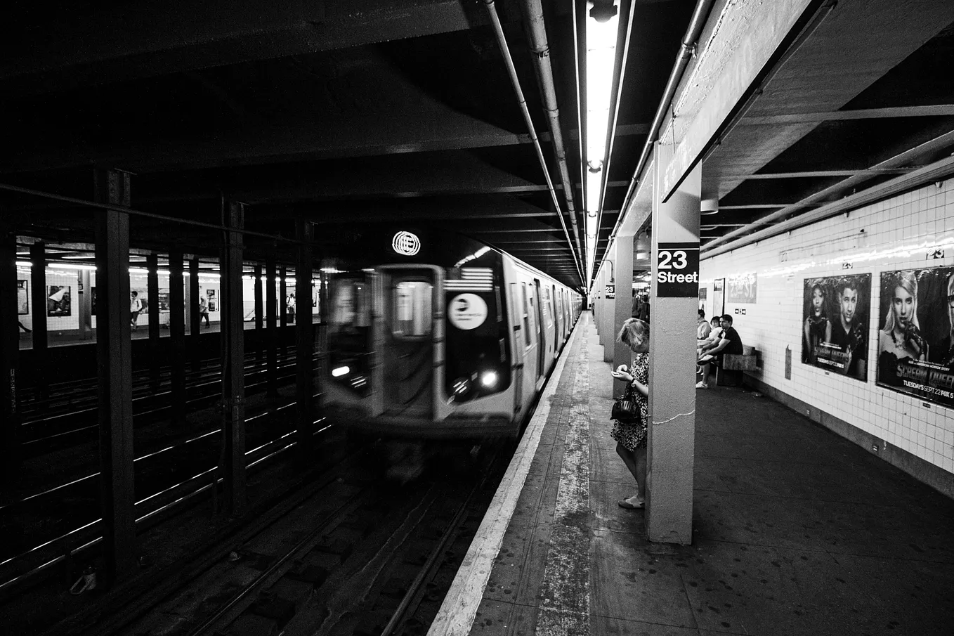 Black and white image of a subway train arriving in a station