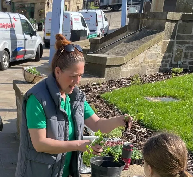 Hayley is helping two small children plant up some pots outside in an urban setting.
