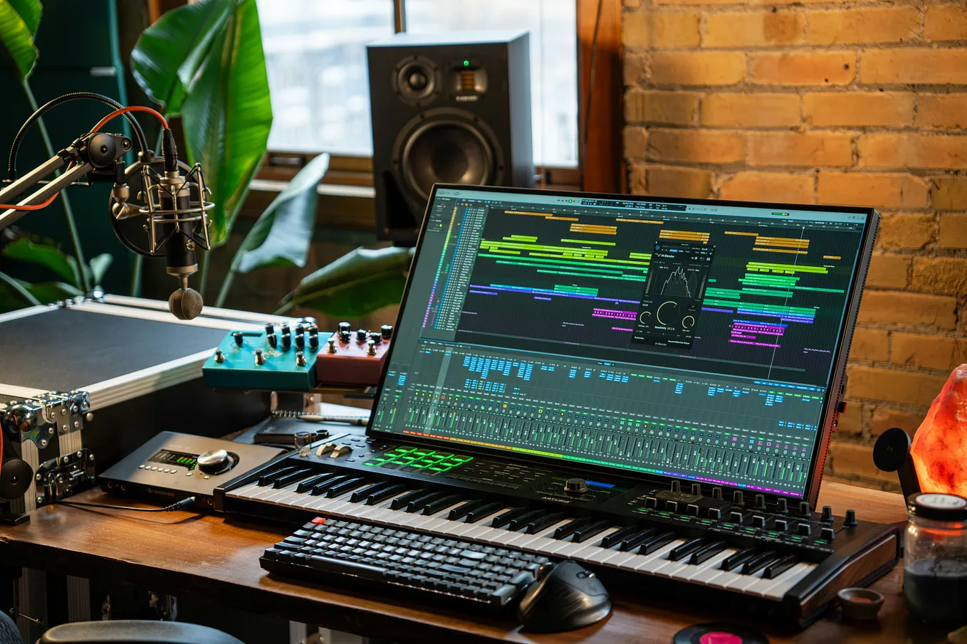 A computer screen, microphone and various electronic boxes and keyboards