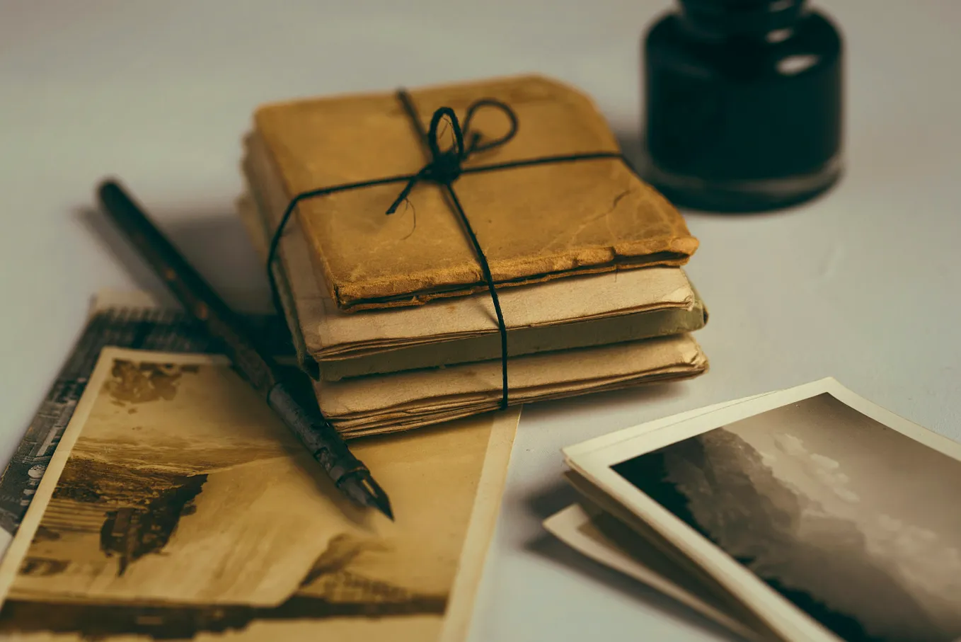 an old fountain pen, a stack of old letters and old faded photographs