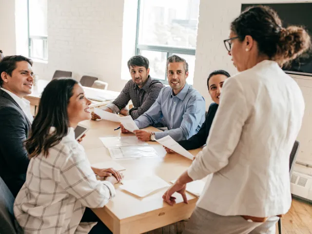 How to Lead When Your Team is Tired, Discouraged and Lost. Image of female leading work team discussion around meeting table.