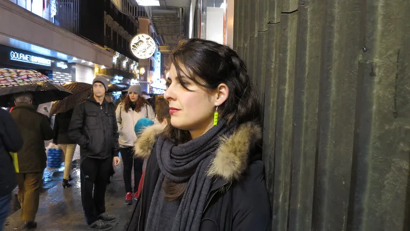 woman leaning against a wall on a city street, listening