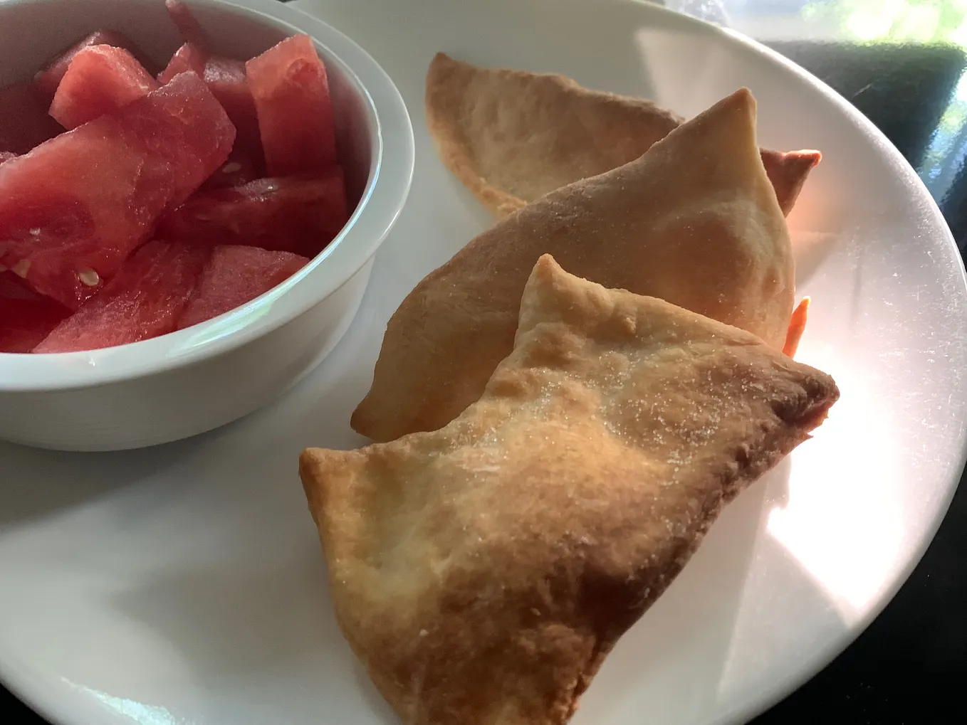 A small dish of sliced watermelon accompanies three glorious Rollkuchen. The perfect pairing of flavour and texture.