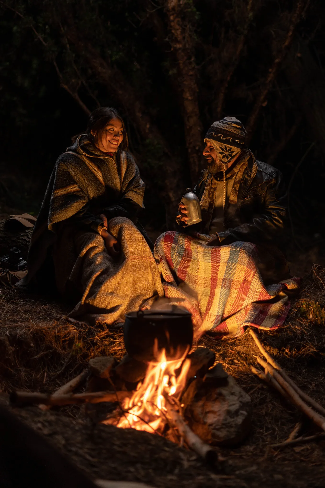 Two people sitting around the glow of a fire