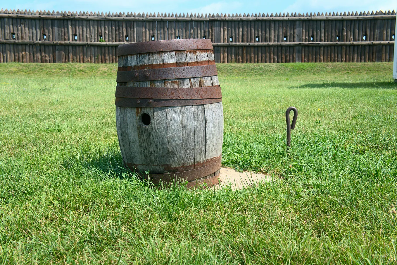 An rusty antique barrel sits on a lawn.