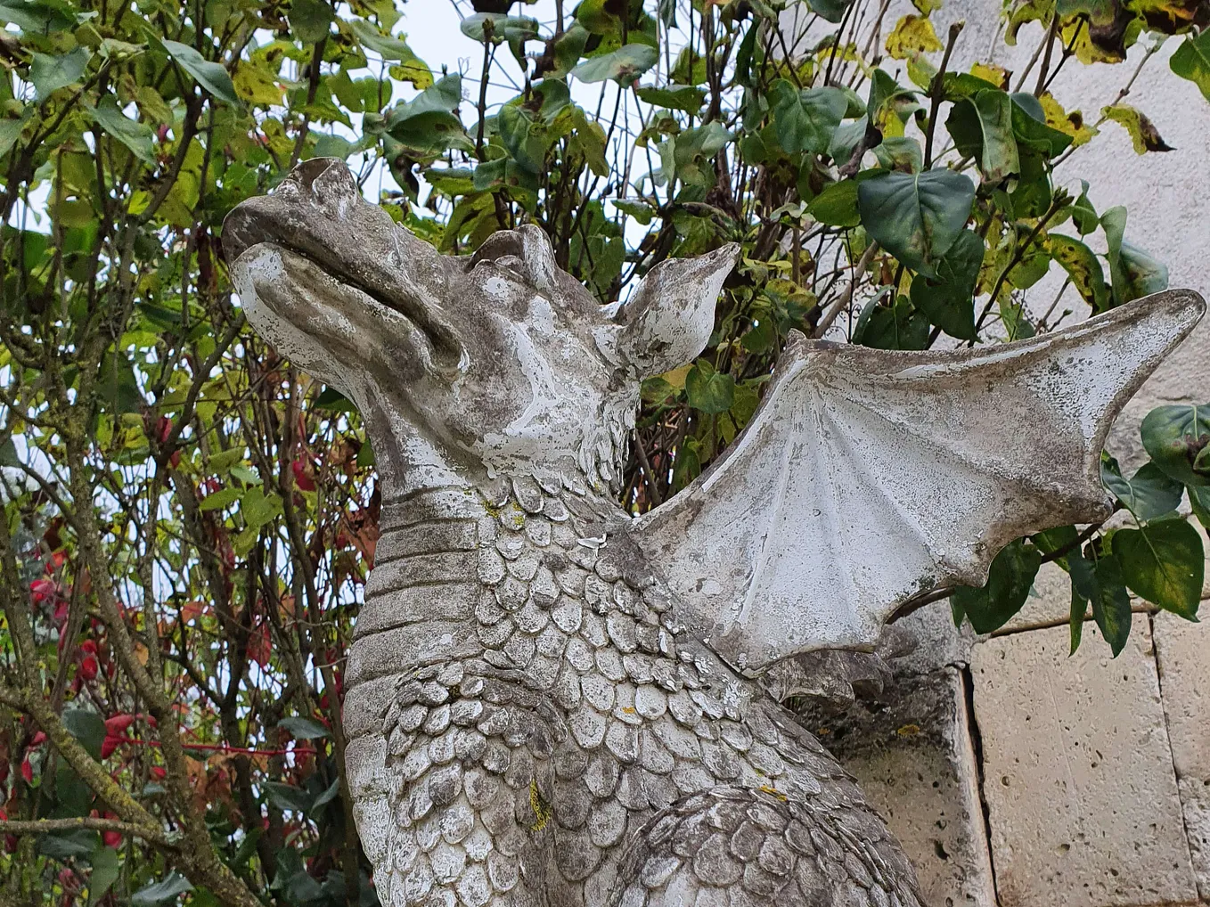A stone statue of a sitting dragon, its snout turned to the sky.