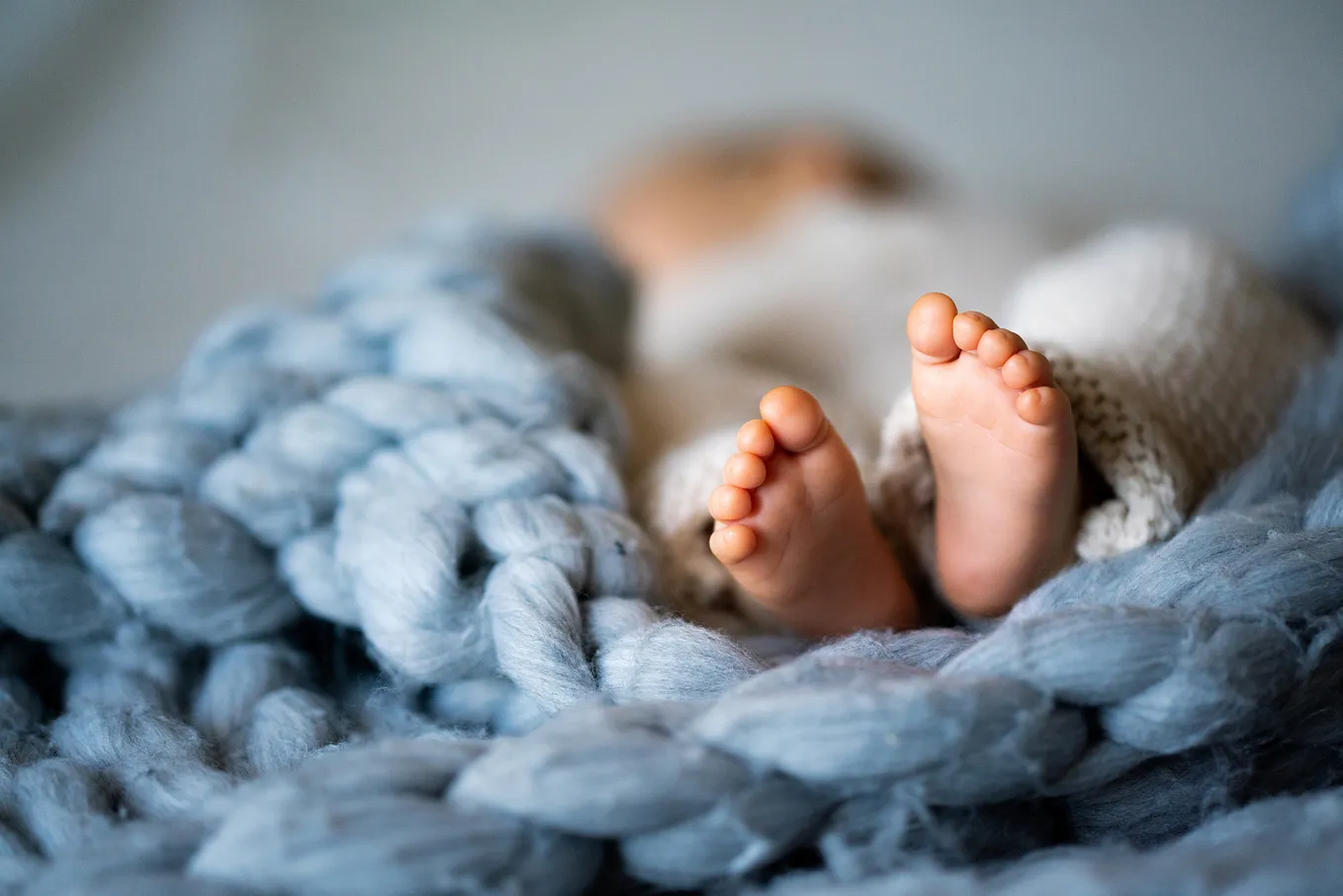 Feet of a newborn baby lying on a warm blanket.