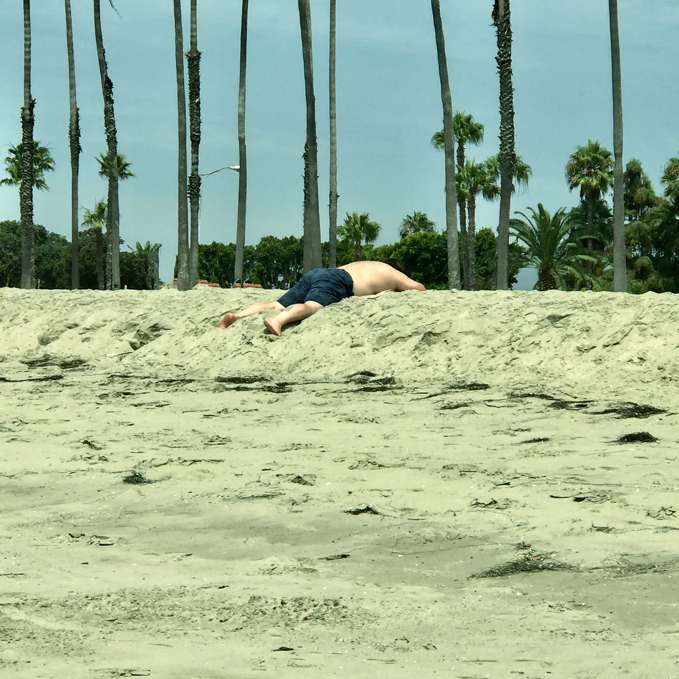 A man faced down in the sand. Photo by Mark Tulin