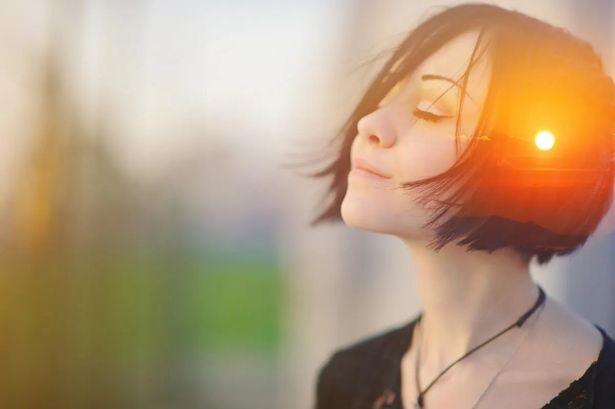A young, brunette, short-haired woman meditating outdoors with eyes closed, combined with photographs of nature, sunrise, or sunset. Body’s wisdom and intuition.