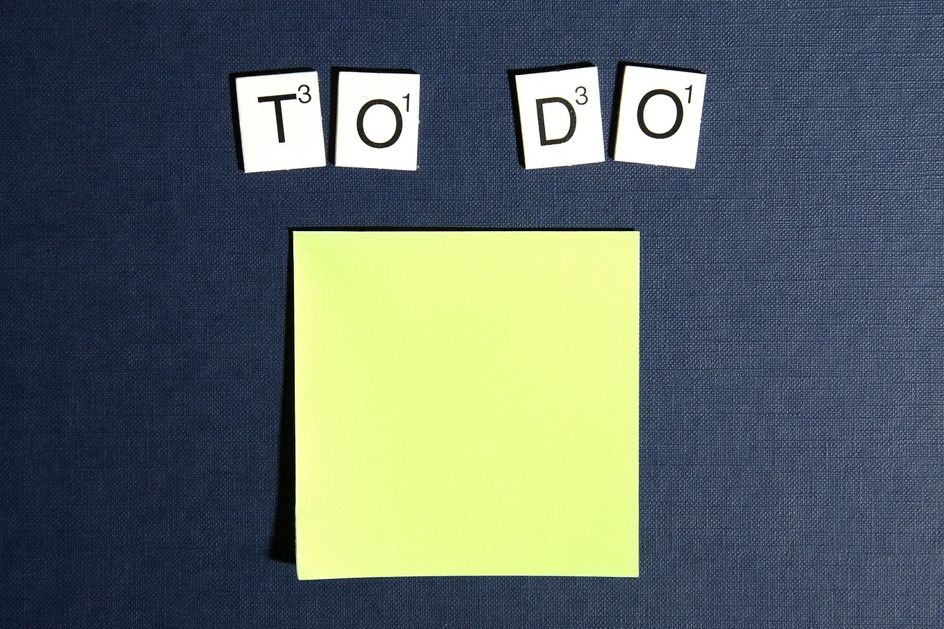 “To Do” written in Scrabble-like letters above a yellow, blank post-it note.