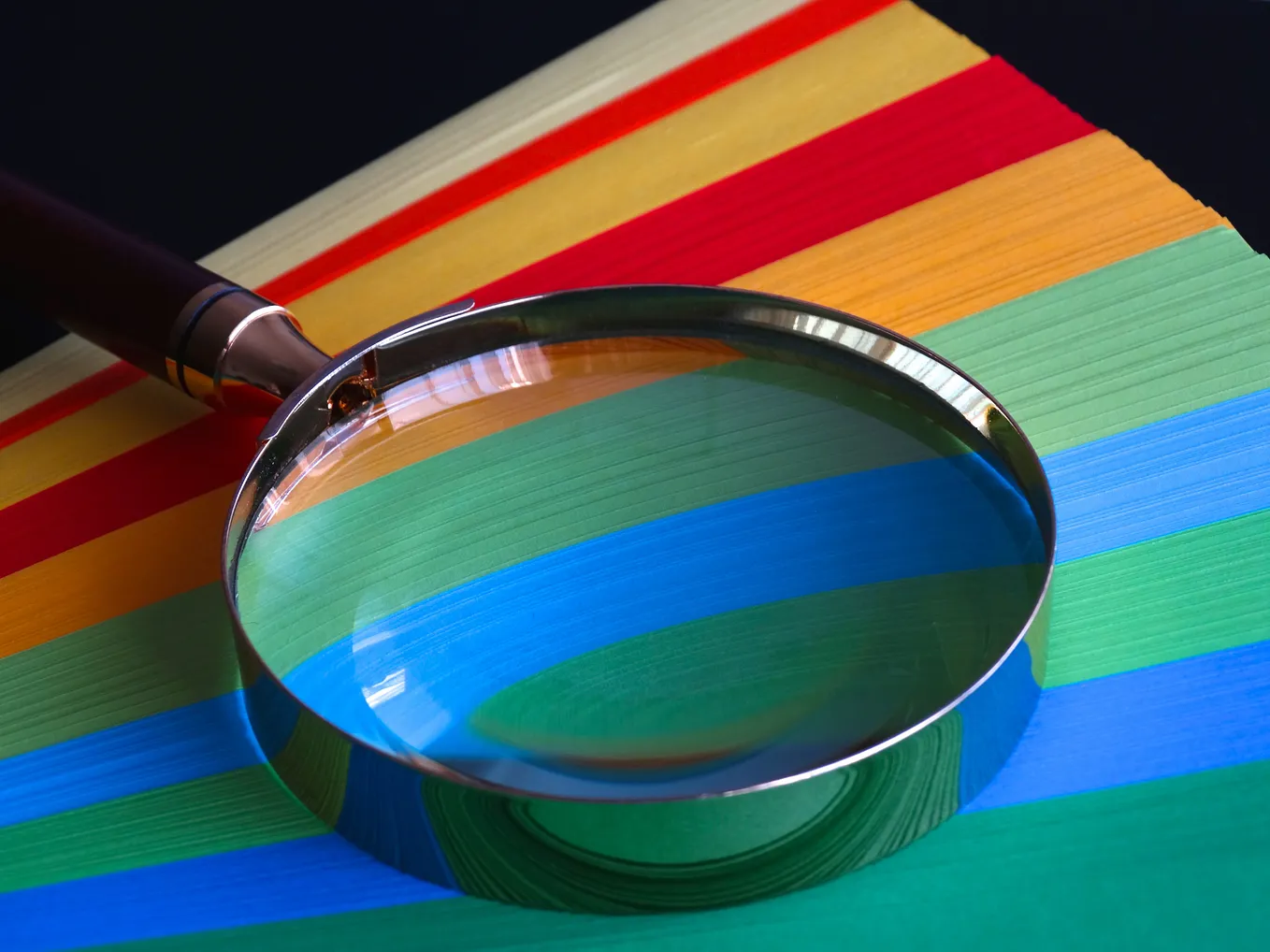 Searching for writer jobs: a magnifying glass lying on top of fanned, brightly colored papers.