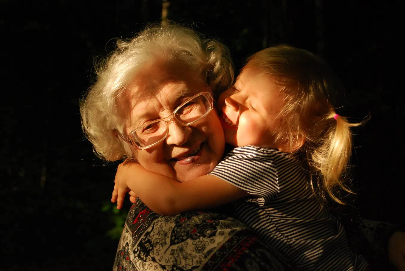 A smiling grandma enjoys the hugs and smiles of her young granddaughter
