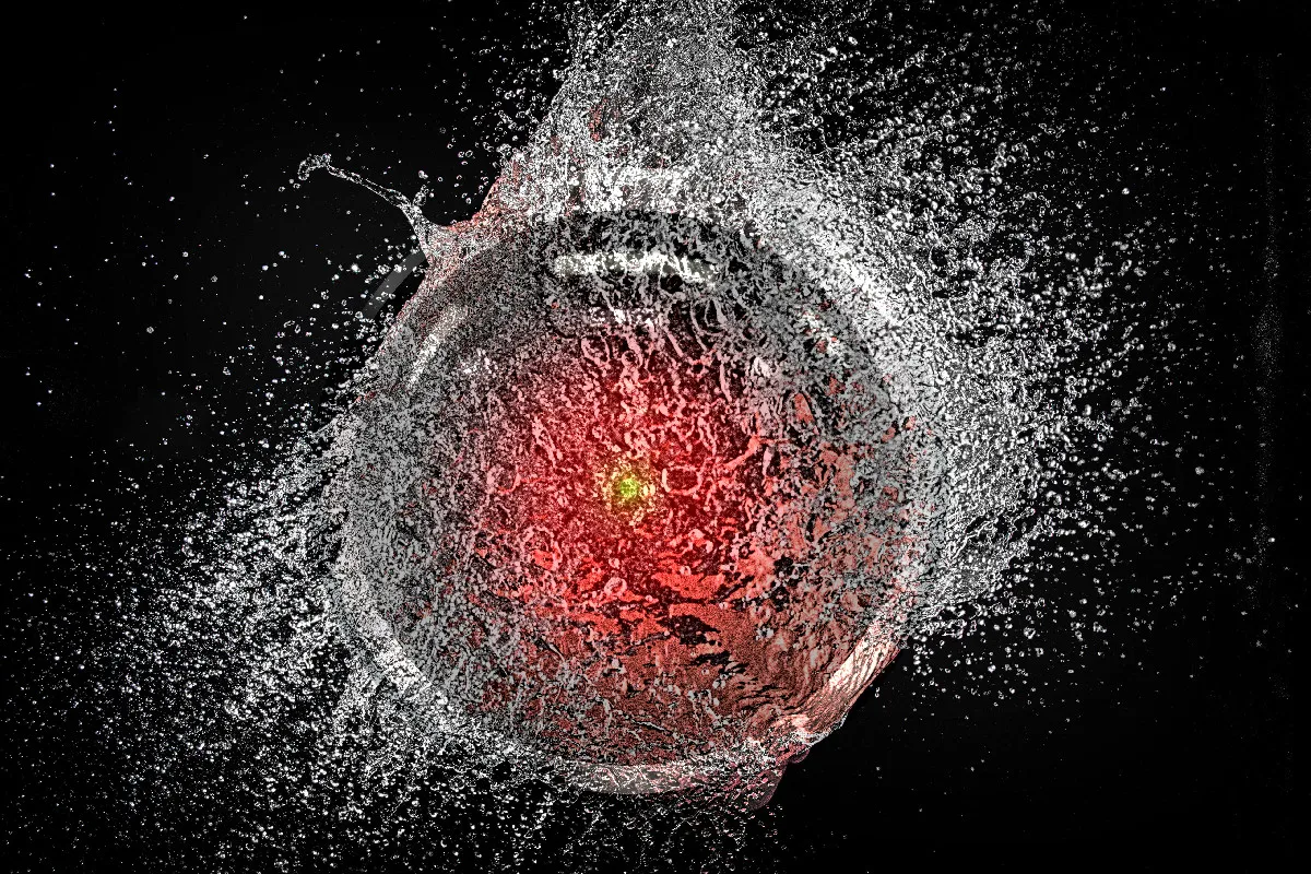 A popping water-balloon, caught mid-burst. Superimposed over it is the hostile glaring eye of HAL9000 from Stanley Kubrick’s ‘2001: A Space Odyssey.’ Image: Cryteria (modified) https://commons.wikimedia.org/wiki/File:HAL9000.svg CC BY 3.0 https://creativecommons.org/licenses/by/3.0/deed.en — tom_bullock (modified) https://www.flickr.com/photos/tombullock/25173469495/ CC BY 2.0 https://creativecommons.org/licenses/by/2.0/