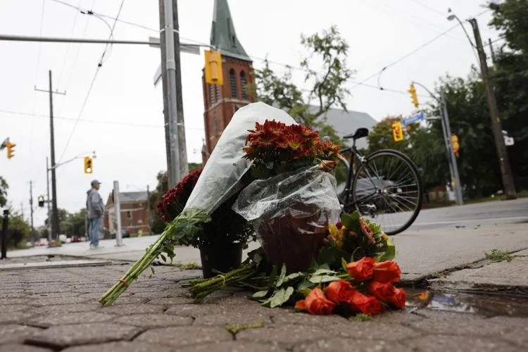 A pile of flowers on the pavement with a building in the background