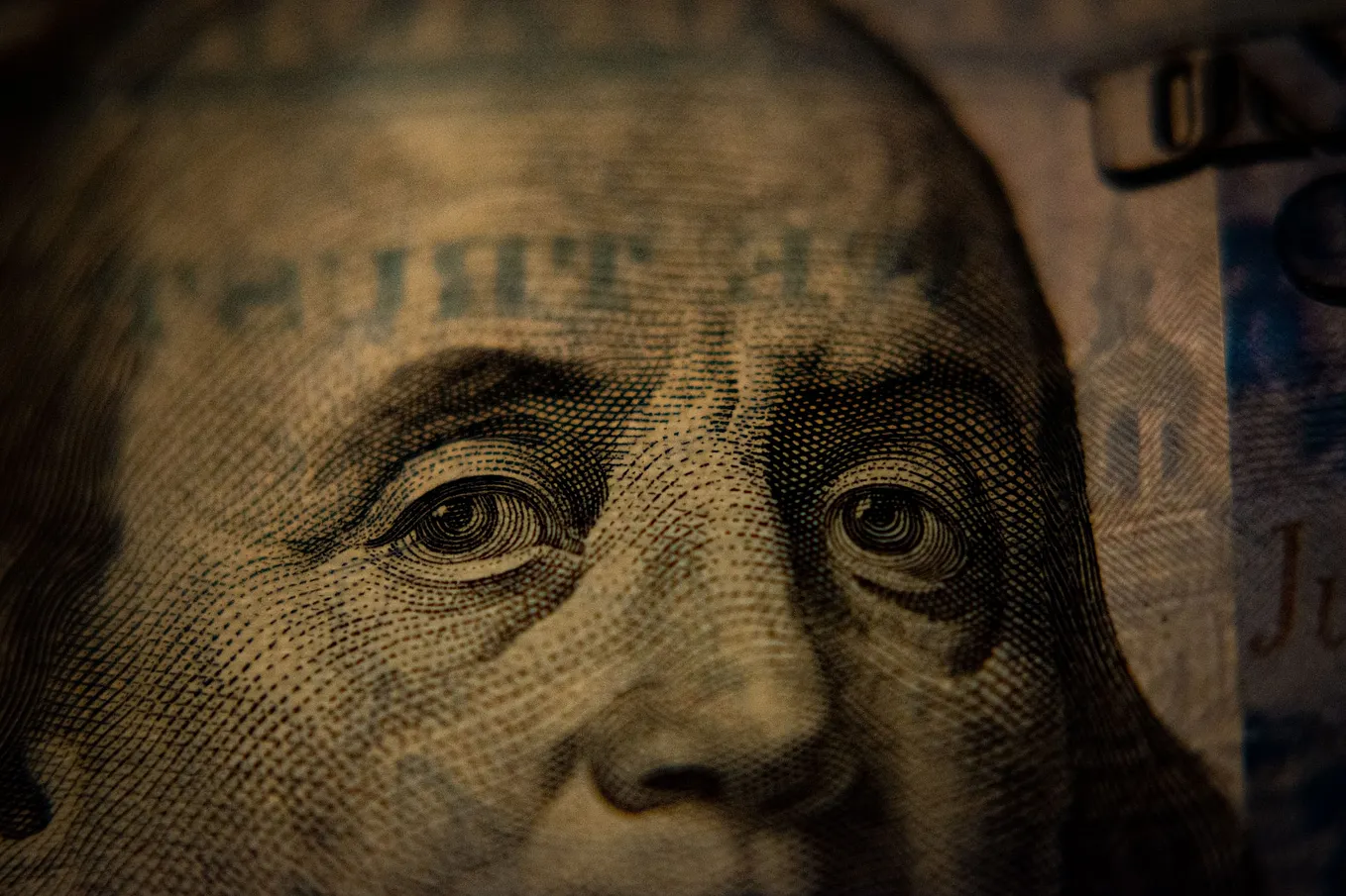 IMAGE: A closeup of a 100 dollars bill, with Ben Franklin looking worried