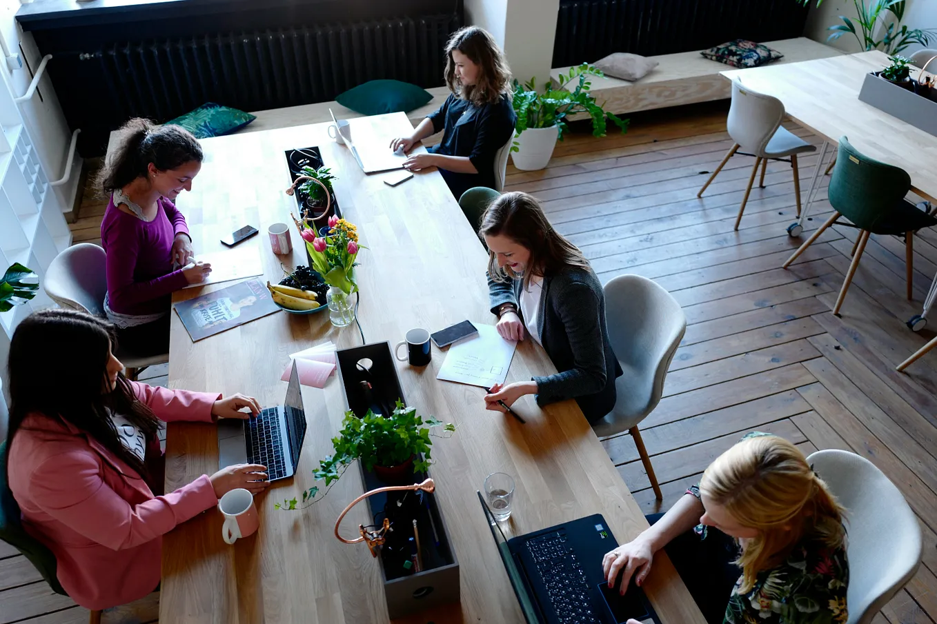 A group of women at work, sitting at a long, wooden table.