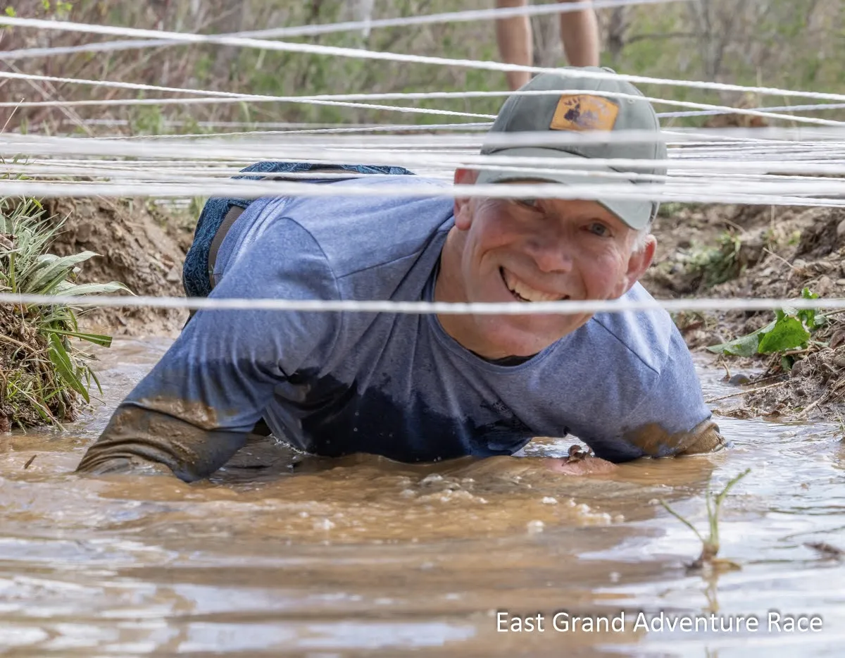 The author smiles as he crawls underneath a web of white cord and into a mid-pit