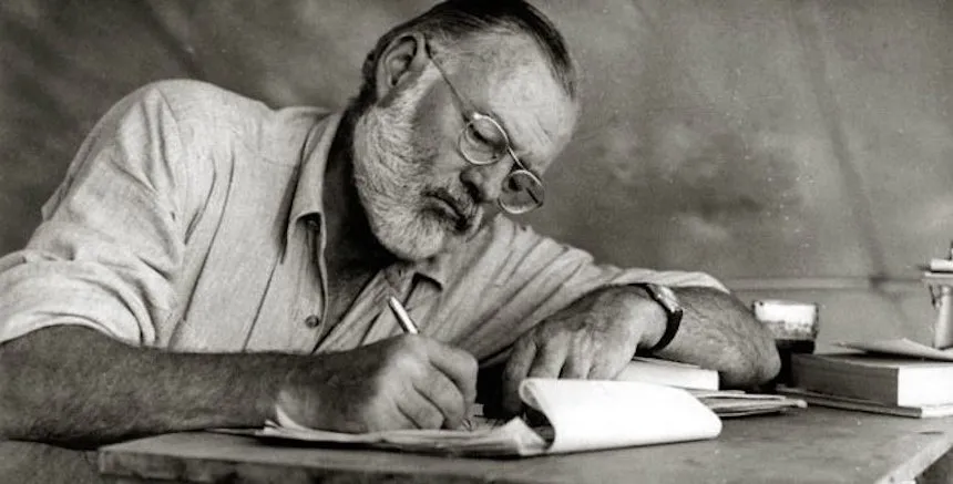 Black-and-white photo of Ernest Hemingway writing in Kenya