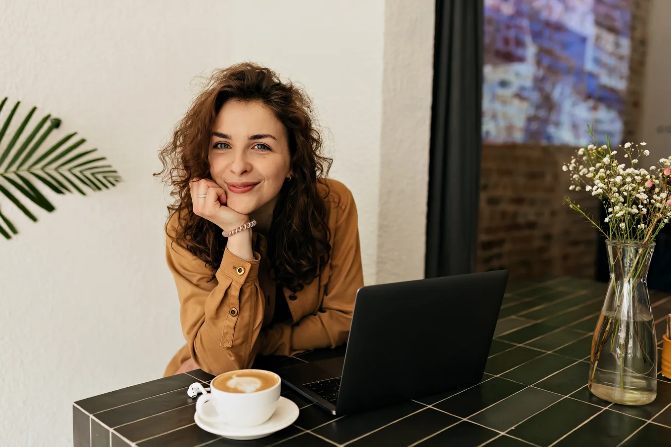 Woman at laptop with coffee smiling at camera