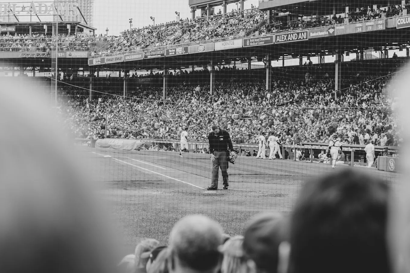 An umpire prepares to dust off the plate at an older era in a Major League Baseball park.