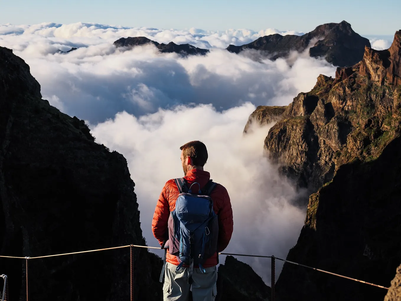 Craig stands on the edge of the trail, overlooking mountains rising from a sea of cloud