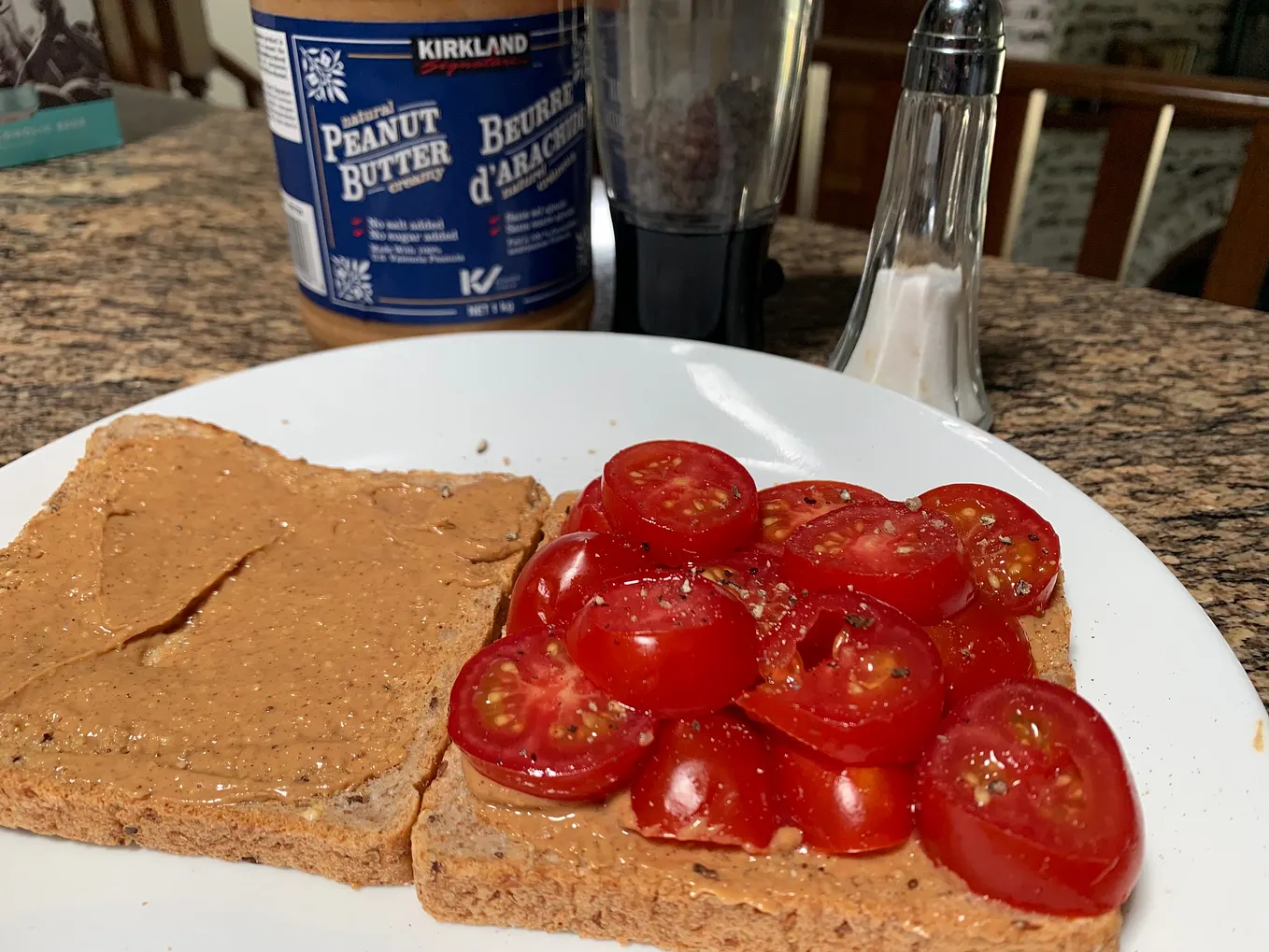An open peanut butter tomato sandwich featuring the ingredients in the background.