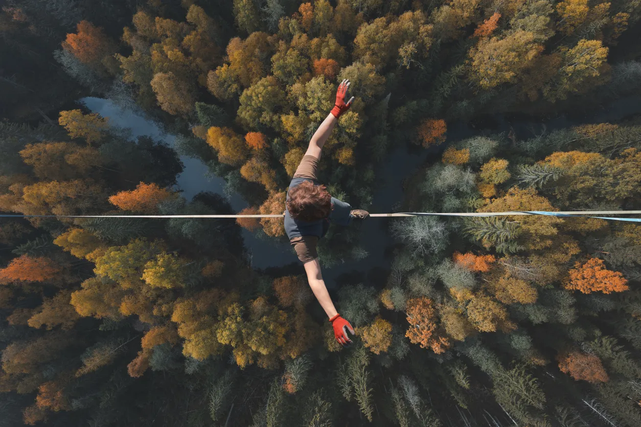 A man walking a tight rope over a forest