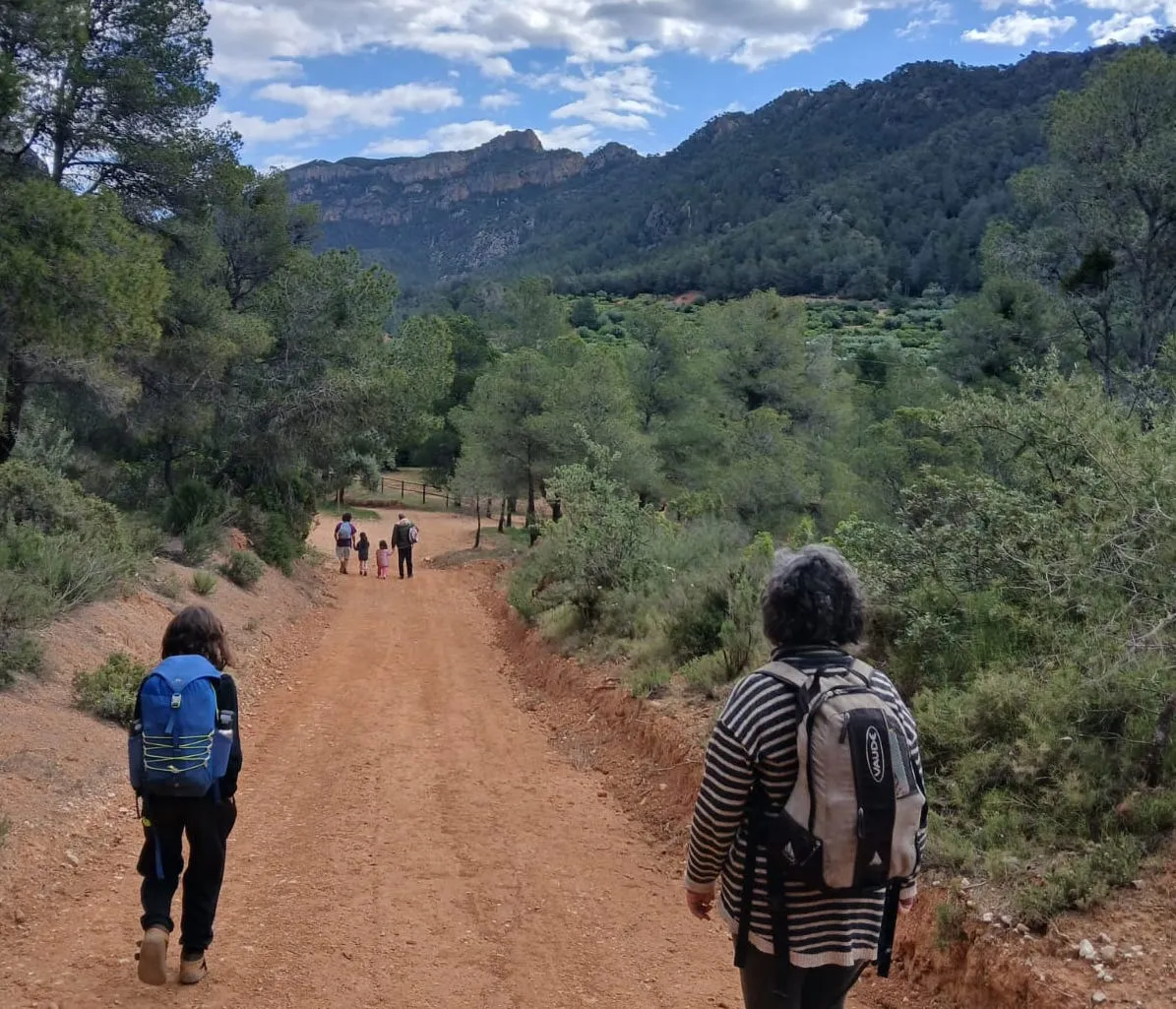 Hiking families walk down a dusty hiking trail in the Catalonian sun