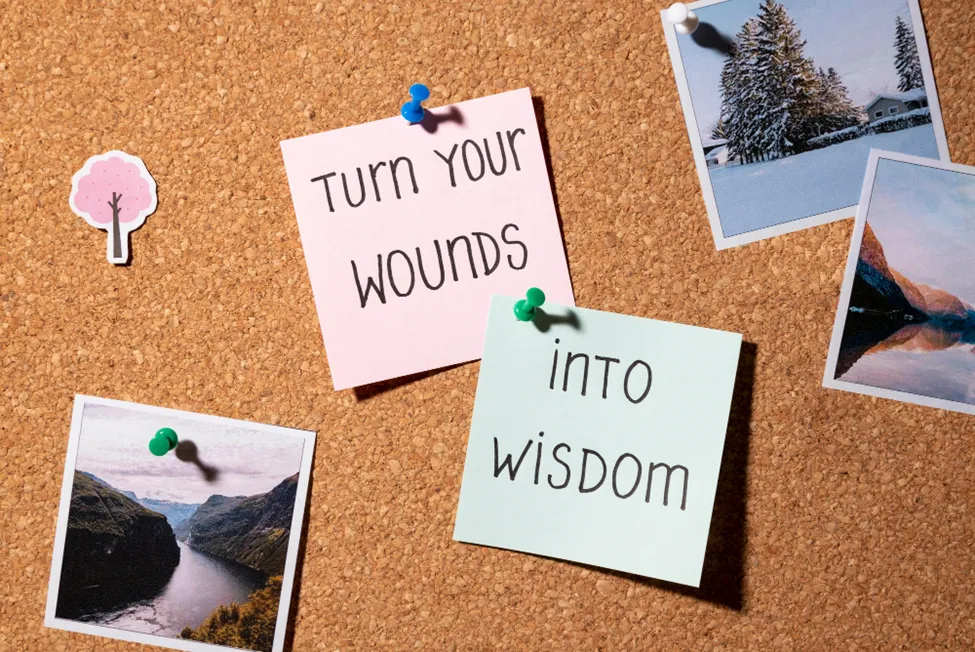 A photo of a bulletin board with sticky notes saying, “Turn your wounds into wisdom.”