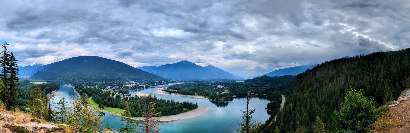 A winding river cuts through jagged mountains in Revelstoke, Canada