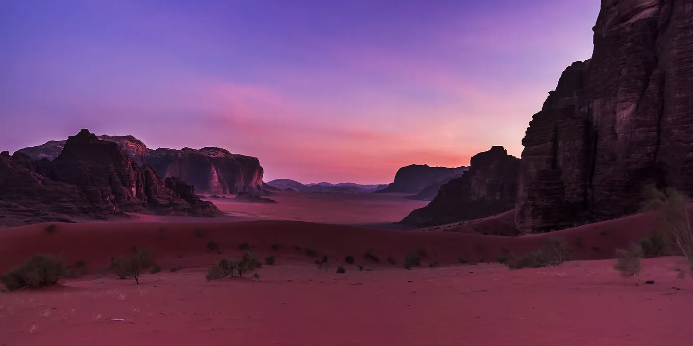 Desert landscape with cliffs in the pinks and purples of sunset.