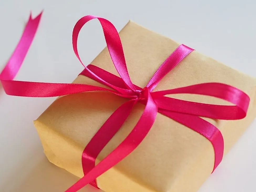 A photo of a paper-wrapped package with a big red ribbon on it.
