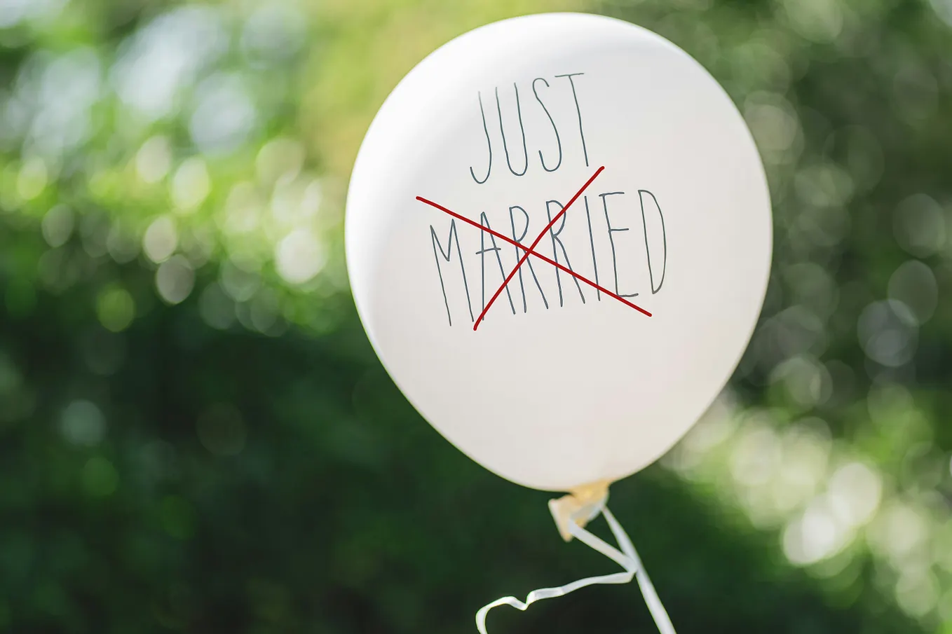 A white balloon with the words “Just Married” handwritten on it, with “Married” crossed out in red.