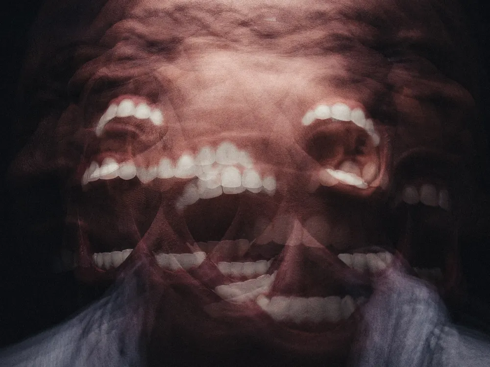 A man screaming using a motion blur effect to obstruct his face, and there are ghost images of his open mouth.
