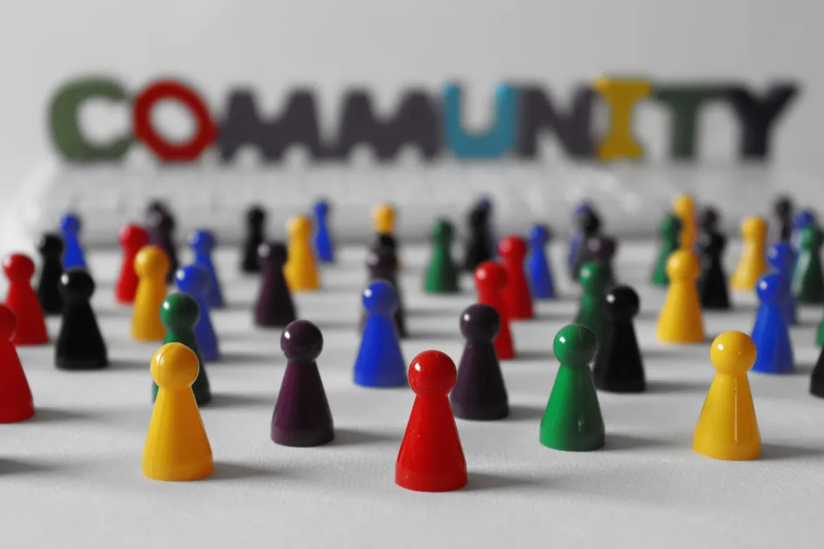 Small game board people pegs in front of the word community