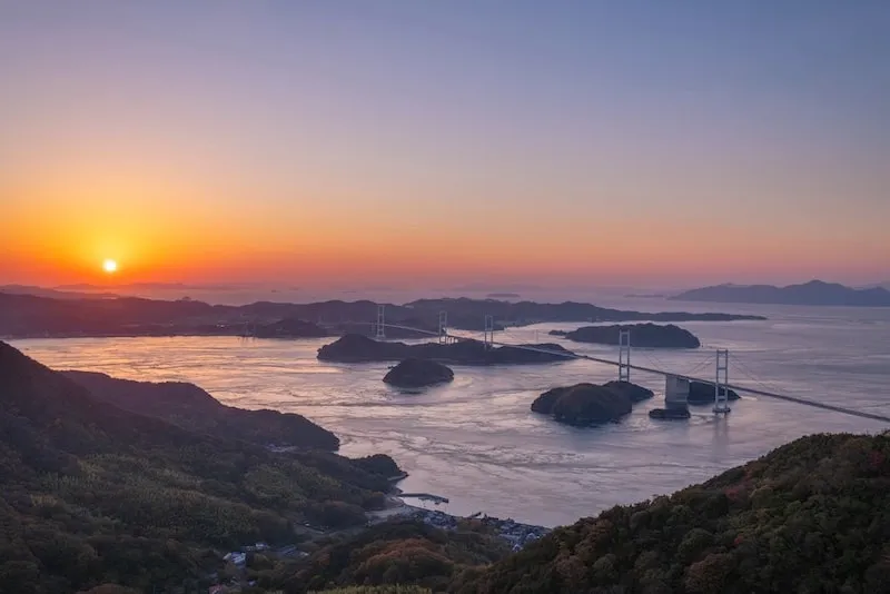 Sunset view of the Kurushima Kaikyo Bridge stretching across the Seto Inland Sea, connecting a series of small islands to the Takanawa Peninsula in Ehime.