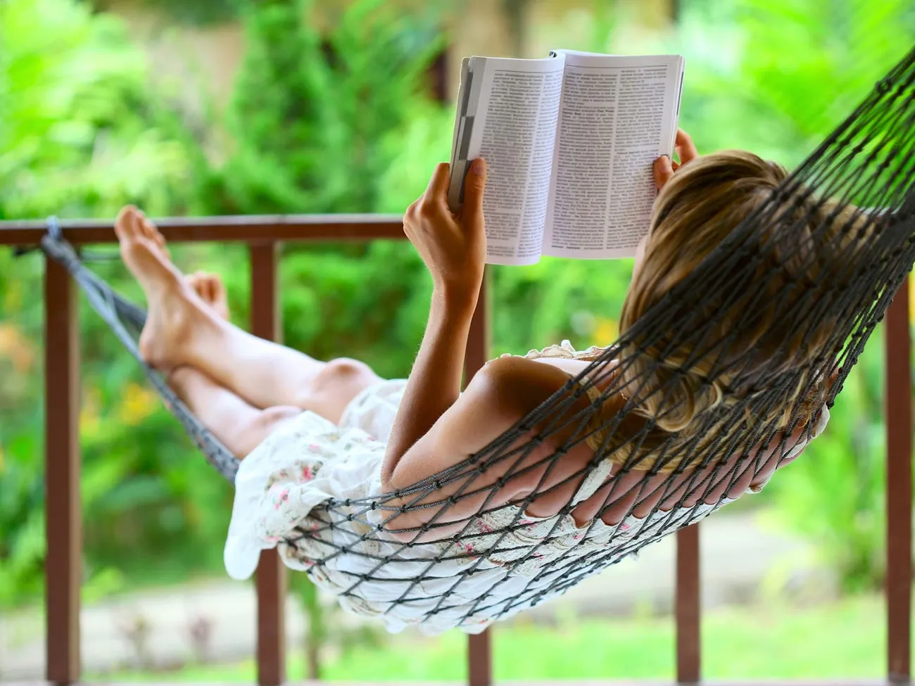 A person reads a book in a hammock.