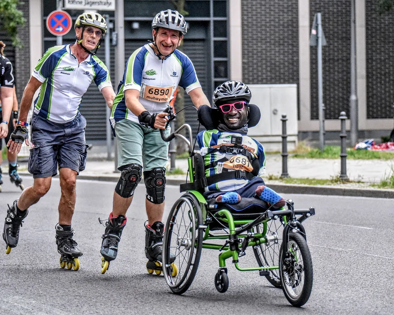 Three men, two rollerblading and one in a wheelchair, are participating in a race.