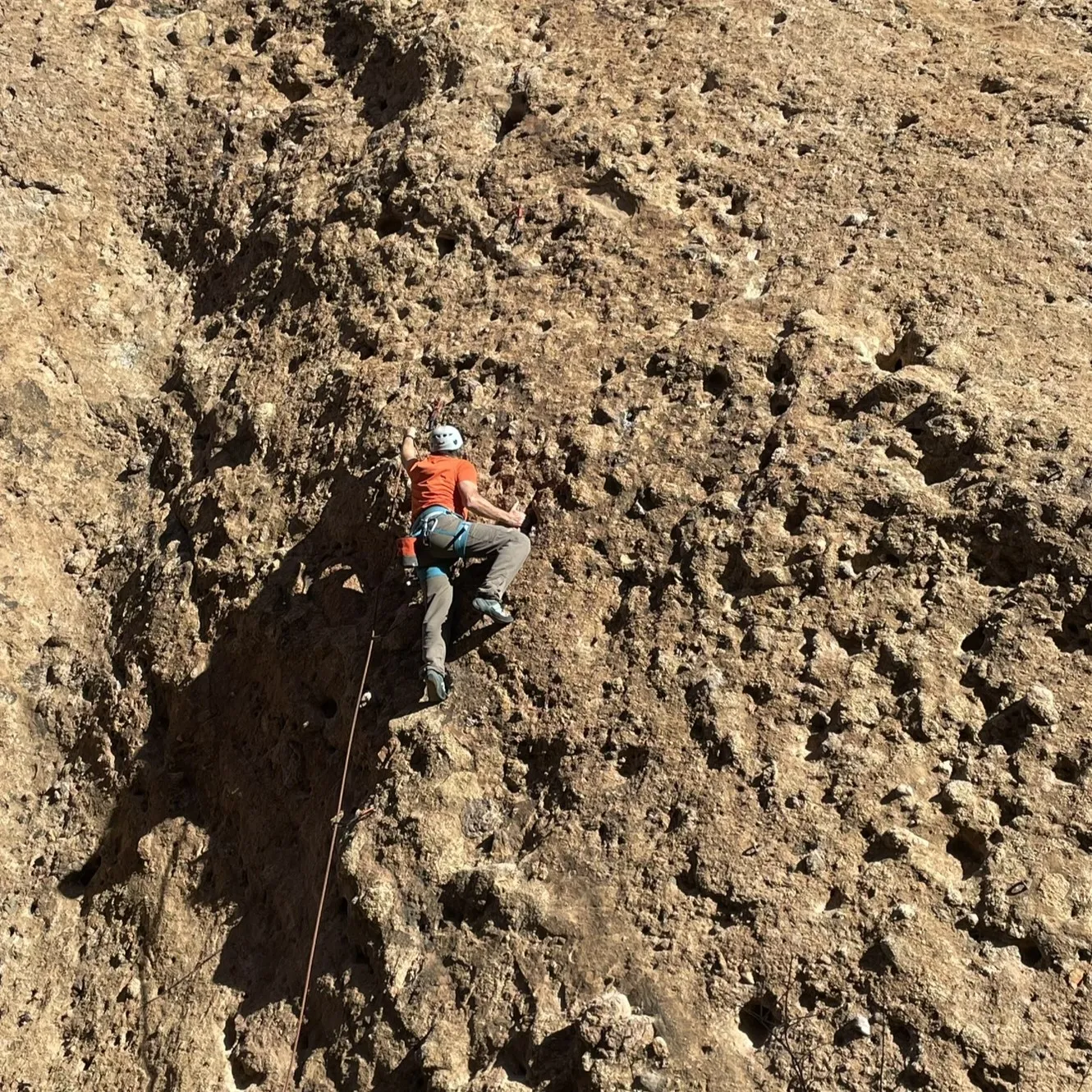 Climber ascends a rugged rock face, showcasing determination and skill.